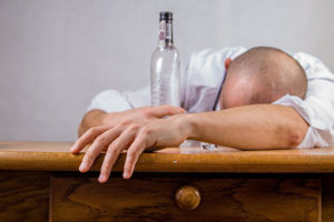 Muž ležící na stole s lahví